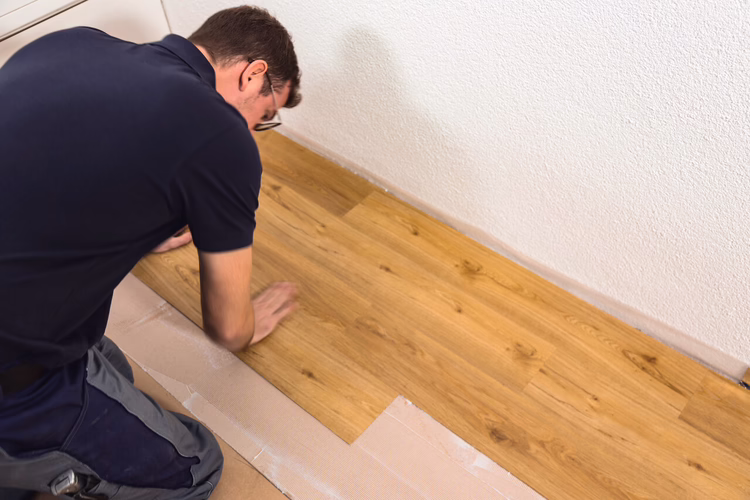 Without bending, install the planks or tiles within the short open time along the reference line and press down firmly by hand. After the installation, roll over the whole area using the WOLFF pressure roller. Cut off any protruding remnants of the PE film after the installation of the floor covering.