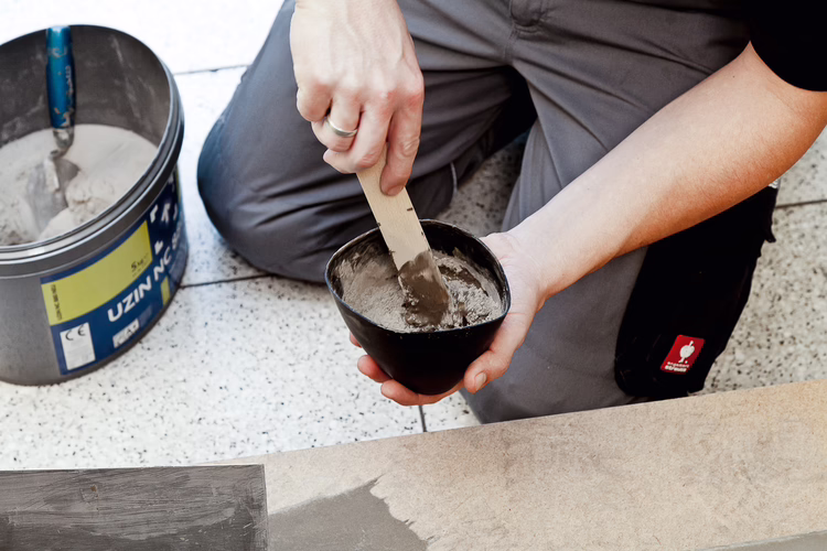 Smoothen major undulations or roughnesses of the surface with low-slump Turbo Levelling Compound UZIN NC 888 S. Pour cold, clean water into a clean container. Sprinkle in the powder whilst mixing vigorously and mix until lump-free. Only mix as much mortar as can be applied within the working time of 5 - 10 minutes.