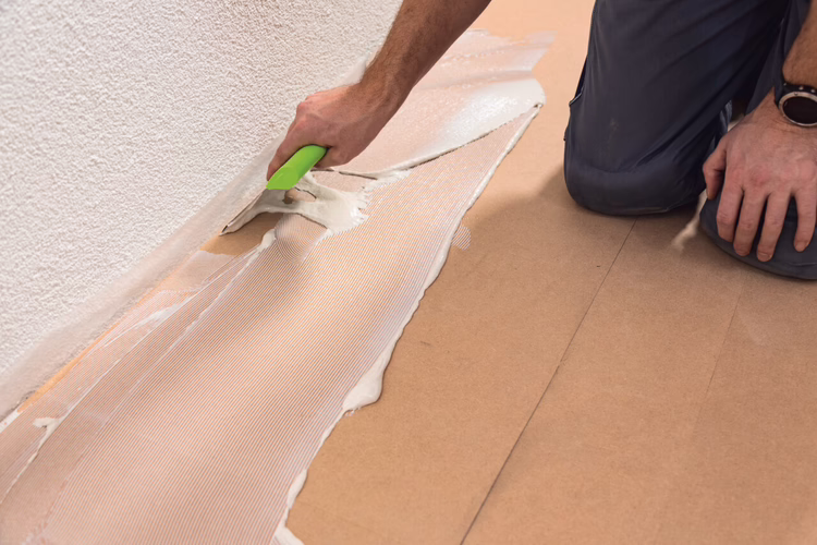 On the RenoTop PLUS Mark the starting point of the first row of planks or tiles with a suitable pen. Spread UZIN KE 66 fibrereinforced adhesive over the surface using notch size A2 along the reference line.